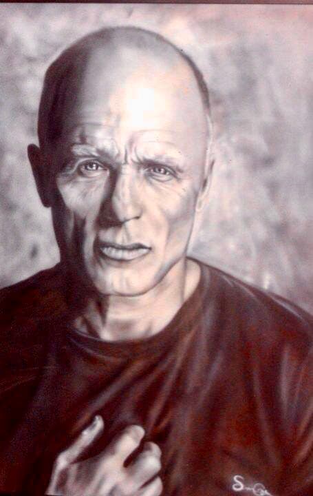 Monochromatic portrait of a bald man with an intense expression and hand on his chest.