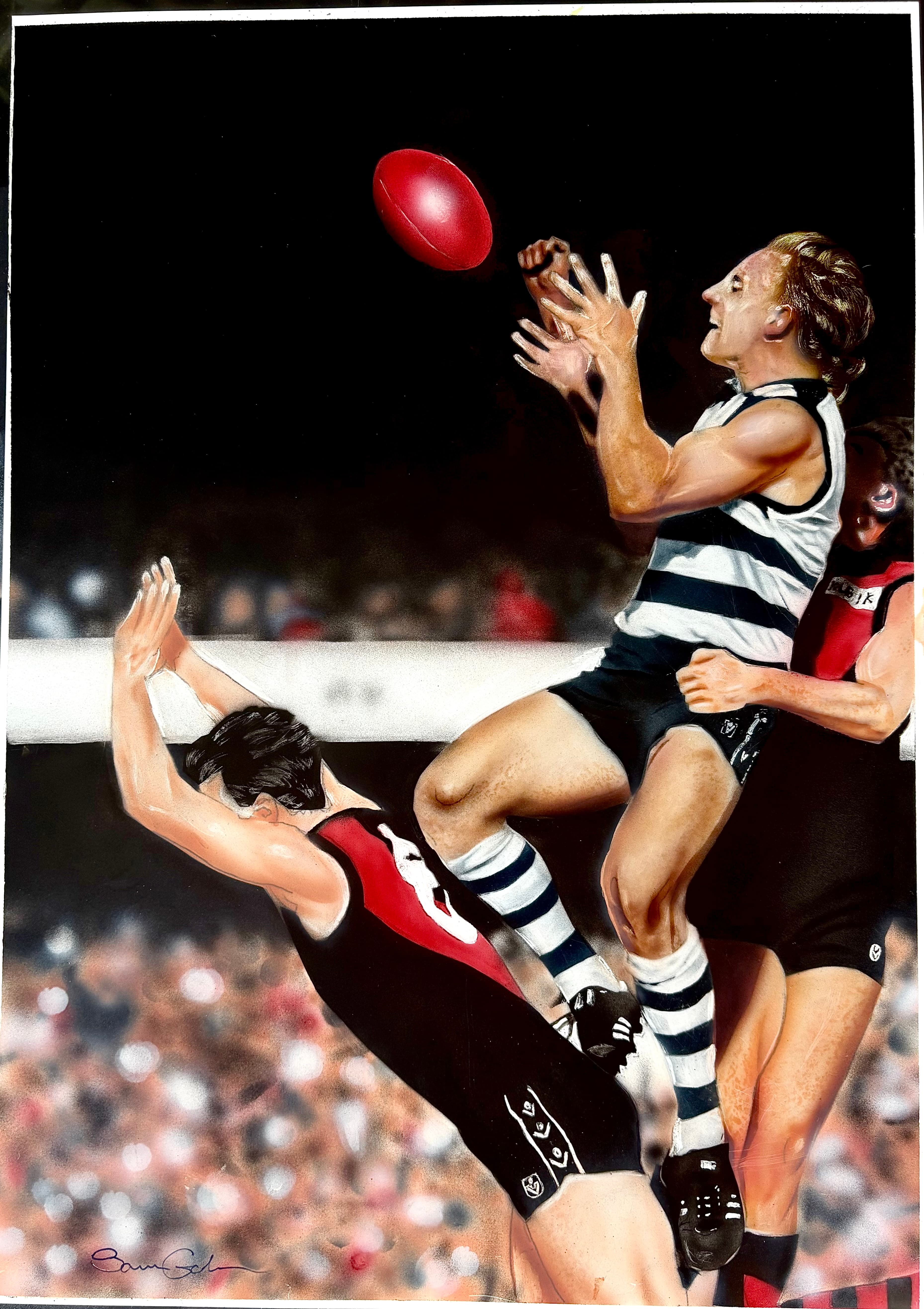 Geelong player leaps high to mark a red football over Essendon opponents at night.